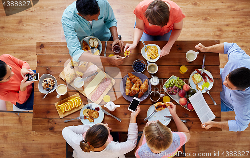 Image of people with smartphones eating food at table