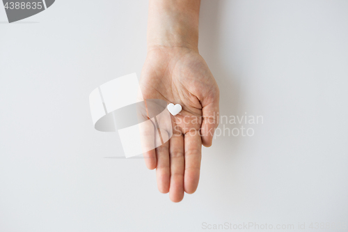 Image of close up of hand holding medicine heart pill