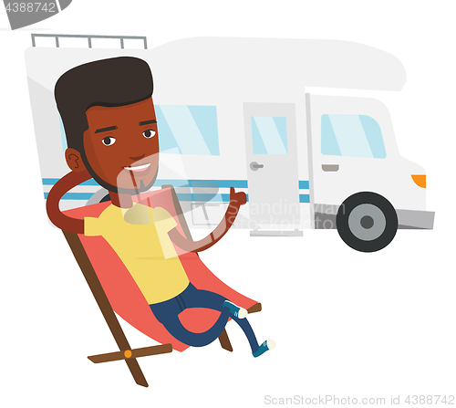 Image of Man sitting in chair in front of camper van.