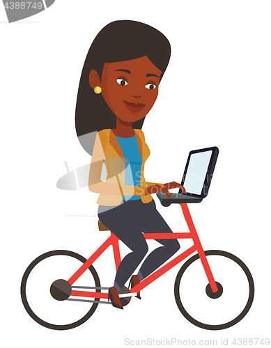 Image of Woman riding bicycle and working on a laptop.