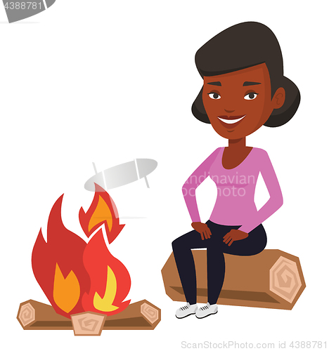 Image of Woman sitting on log near campfire in the camping.