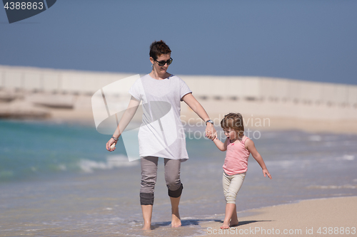 Image of mother and daughter running on the beach