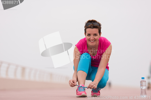 Image of Young woman tying shoelaces on sneakers