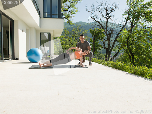 Image of woman with personal trainer doing morning yoga exercises