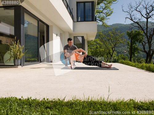 Image of woman with personal trainer doing morning yoga exercises