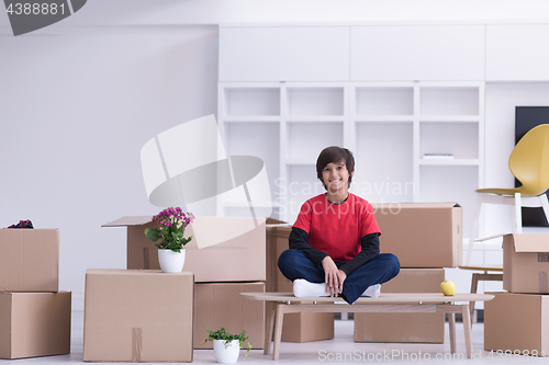 Image of boy sitting on the table with cardboard boxes around him