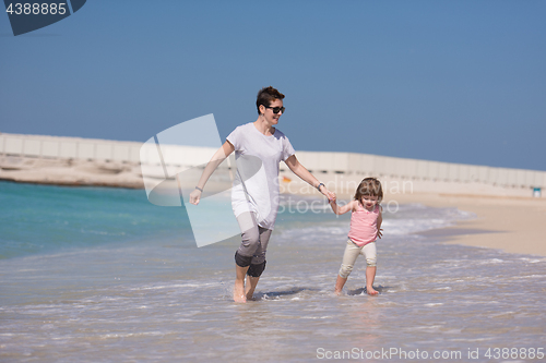 Image of mother and daughter running on the beach