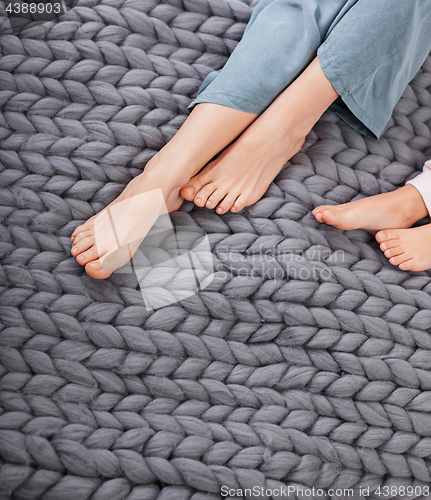 Image of Mother and daughter legs on woolen knitted plaid