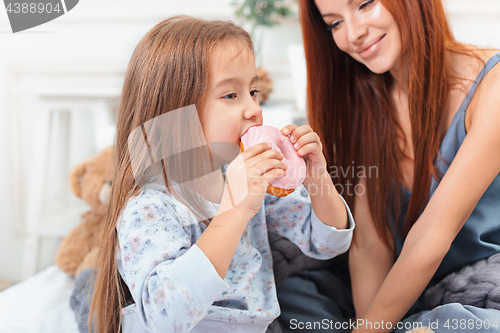 Image of A little cute girl enjoying, playing and creating with cake with mother