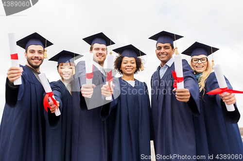 Image of happy students in mortar boards with diplomas