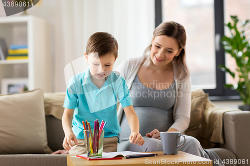 Image of pregnant mother and son with workbook at home