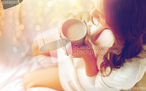 Image of close up of woman with cocoa cup in bed at home