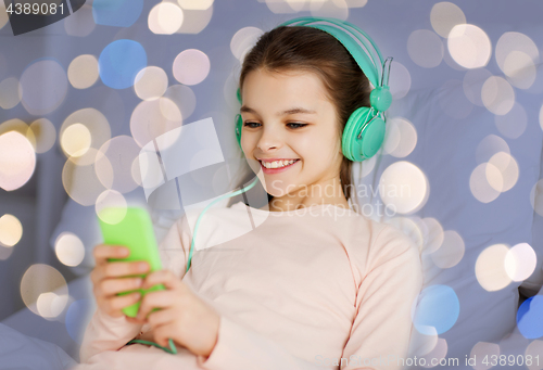 Image of girl in headphones with smartphone over lights