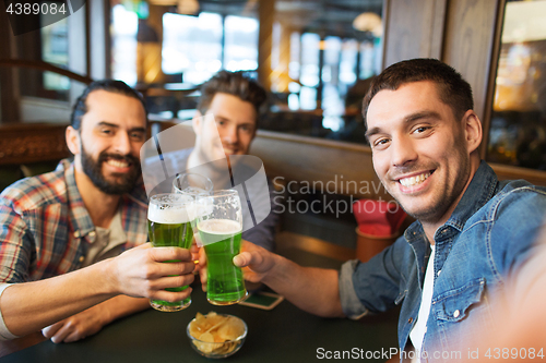 Image of friends with green beer taking selfie at pub