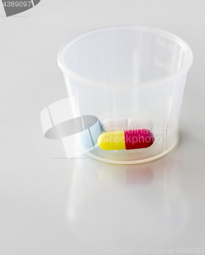 Image of close up of pills and capsule in medicine cup