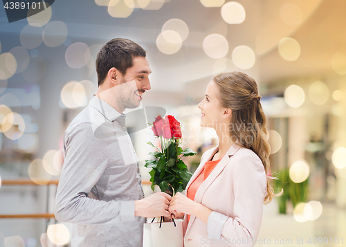 Image of happy young couple with flowers in mall