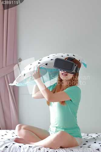 Image of Young woman wearing virtual reality glasses at home.