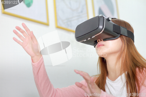 Image of Young woman wearing virtual reality glasses at home.