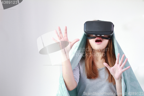 Image of Young woman wearing virtual reality glasses at home.