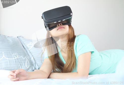 Image of Young woman wearing virtual reality glasses at home.