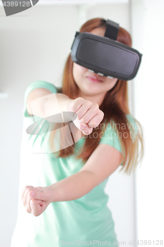 Image of Young woman wearing virtual reality glasses at home.