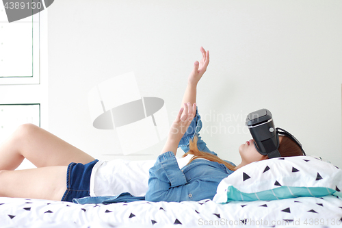 Image of Young woman wearing virtual reality glasses at home.