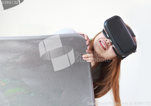 Image of Young woman wearing virtual reality glasses at home.