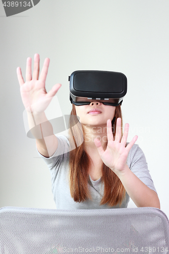 Image of Young woman wearing virtual reality glasses at home.