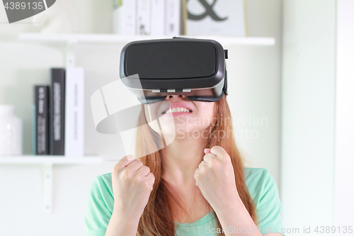 Image of Young woman wearing virtual reality glasses at home.