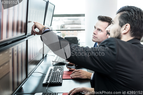 Image of Stock traders looking at market data on computer screens.