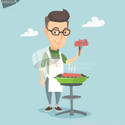 Image of Man cooking steak on barbecue grill.