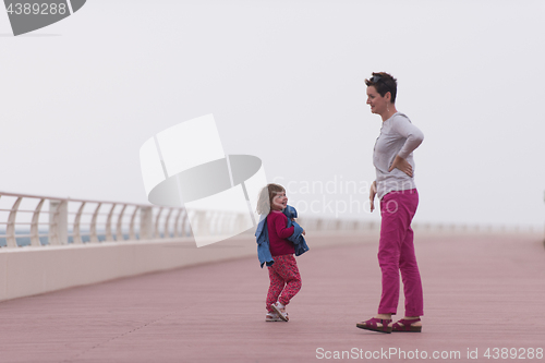 Image of mother and cute little girl on the promenade by the sea