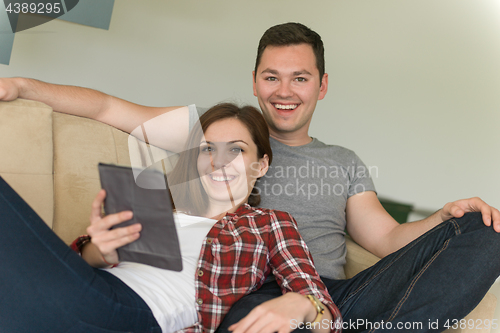 Image of couple relaxing at  home with tablet computers