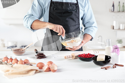 Image of A cook with eggs on a rustic kitchen against the background of men\'s hands