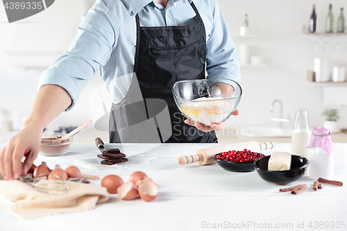 Image of A cook with eggs on a rustic kitchen against the background of men\'s hands