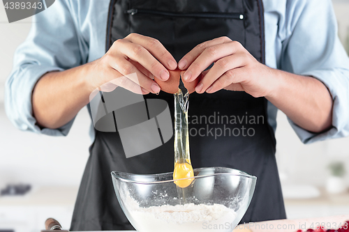 Image of A cook with eggs on a rustic kitchen against the background of men\'s hands