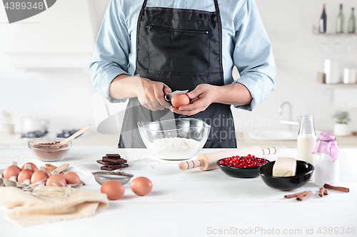 Image of A cook with eggs on a rustic kitchen against the background of men\'s hands