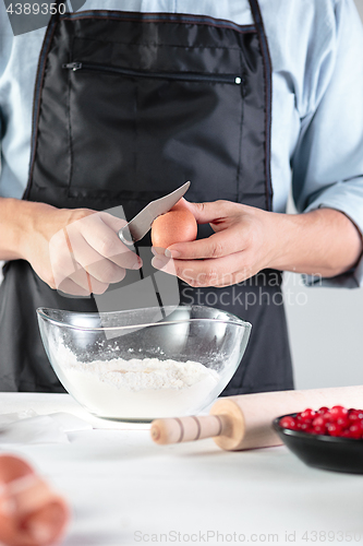 Image of A cook with eggs on a rustic kitchen against the background of men\'s hands