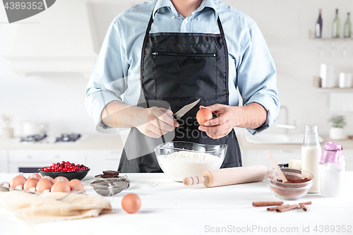 Image of A cook with eggs on a rustic kitchen against the background of men\'s hands