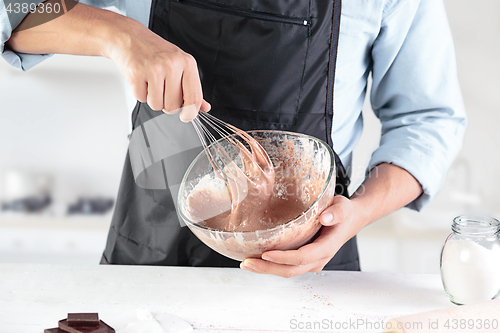 Image of A cook with eggs on a rustic kitchen against the background of men\'s hands