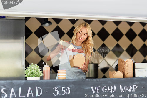 Image of happy saleswoman making wok at food truck