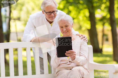 Image of happy senior couple with tablet pc at summer park