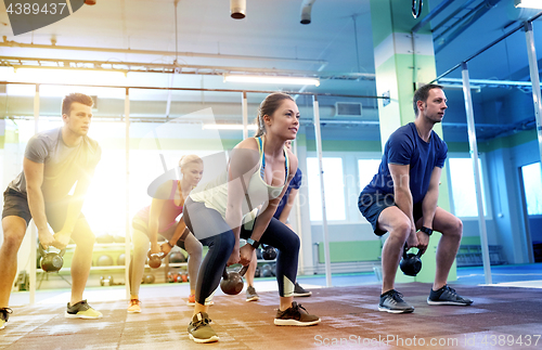 Image of group of people with kettlebells exercising in gym