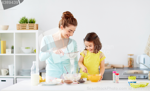 Image of happy mother and daughter baking at home