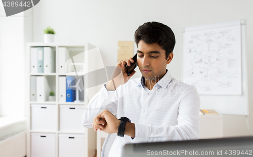 Image of businessman calling on smartphone at office