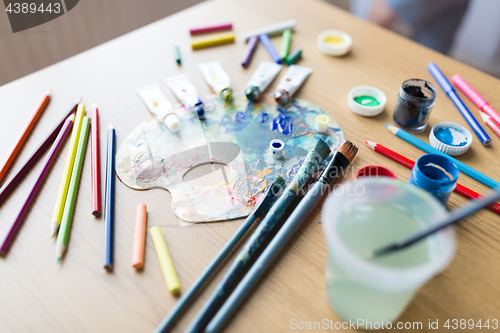 Image of color palette, brushes and paint tubes on table