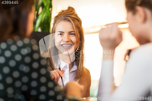 Image of happy friends sitting and talking at cafe