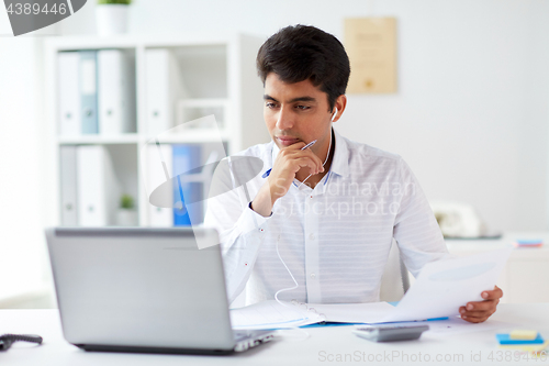 Image of businessman in earphones working at office