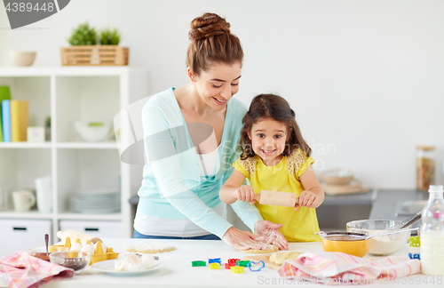 Image of happy mother and daughter making cookies at home