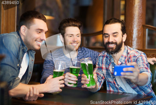 Image of friends taking selfie with green beer at pub